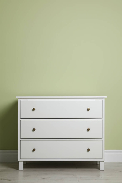Modern white chest of drawers near light green wall indoors - Foto, Imagem