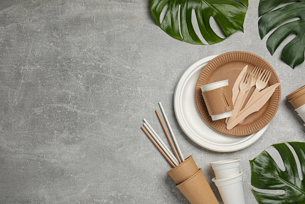 Flat lay composition with disposable tableware and monstera leaves on light grey background, space for text - Photo, Image
