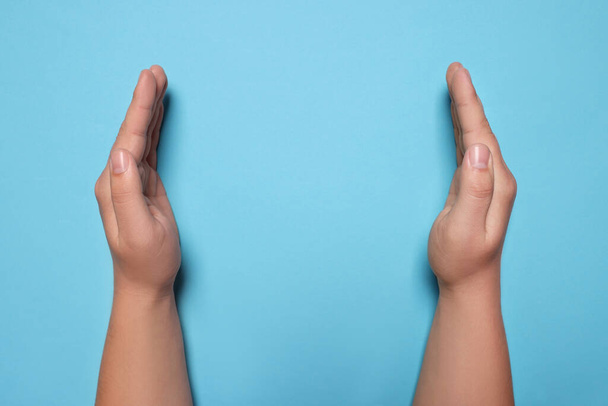 Woman holding on light blue background, closeup of hands. Space for text - Foto, afbeelding