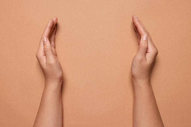 Woman holding on coral background, closeup of hands. Space for text - Fotoğraf, Görsel