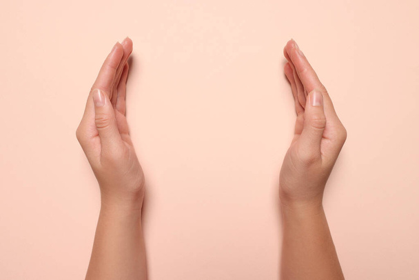 Woman holding on pale pink background, closeup of hands. Space for text - Foto, afbeelding