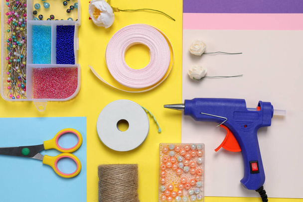 Flat lay composition with hot glue gun and handicraft materials on color background - Foto, Imagem