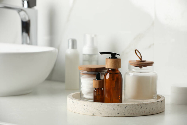 Tray with dispenser bottle and cosmetic products on white table in bathroom - Foto, afbeelding