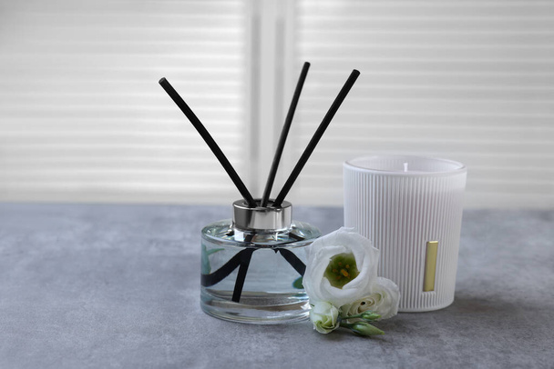 Reed diffuser, scented candle and eustoma flowers on gray marble table - Foto, Bild