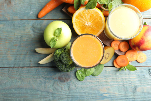 Glasses of delicious juices and fresh ingredients on blue wooden table, flat lay - Foto, Imagen