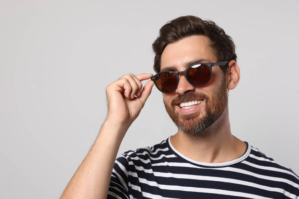 Portrait of smiling bearded man with stylish sunglasses on light grey background. Space for text - Zdjęcie, obraz