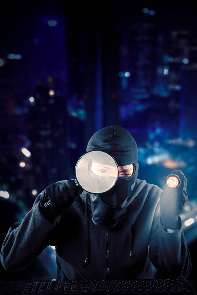Male hacker holding a magnifier and flashlight to stealing data in the cyberspace - Foto, immagini