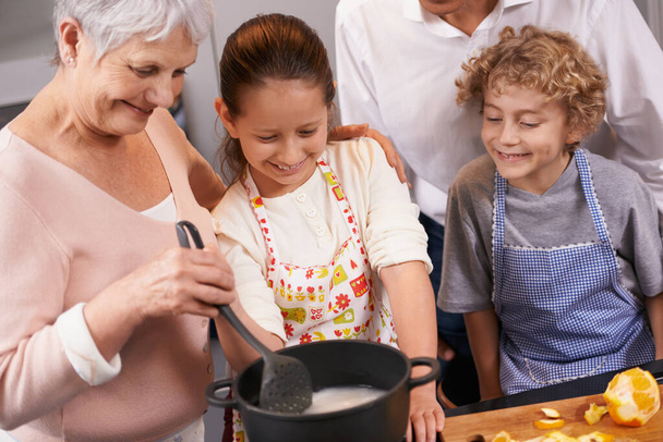 誰もおばあちゃんより料理がうまい。彼らの祖父母の家で夕食を作るのを手伝っている兄弟姉妹 - 写真・画像