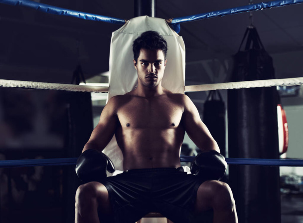Er fand seinen Platz im Boxring. Porträt eines jungen männlichen Boxers, der in einer Ecke eines Boxrings sitzt - Foto, Bild