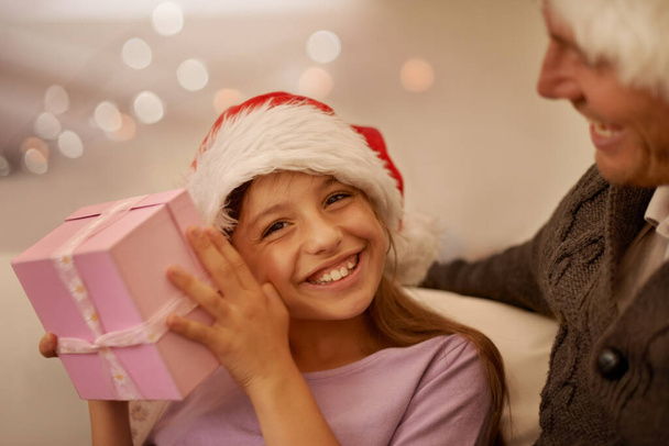 Christmas is for the kids. Smiling girl shaking her present to try and guess whats inside - Fotó, kép