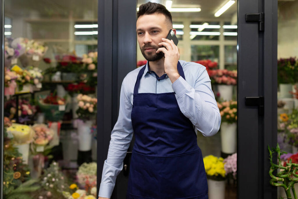 florista hombre de negocios hablando por teléfono al lado del refrigerador con flores. - Foto, Imagen