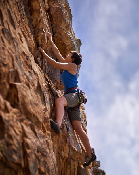 So near to her goal. A young woman reaching to clip a bolt while rock climbing - Photo, Image