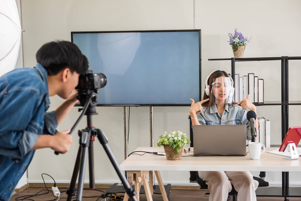 Behind the scene concept. Videographer record footage to streaming live online of young Asian women blogger with face mask with studio lighting. broadcasting vlogger content of internet influencer. - 写真・画像