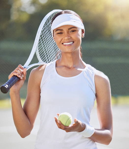Tennis, fitness and sport woman with racket for training, exercise and workout on tennis court. Portrait, smile and motivation with tennis ball for energy, health wellness or winner mindset for match. - 写真・画像
