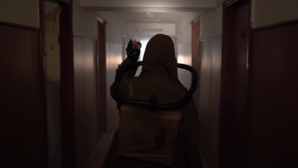 Vue arrière d'un survivant de l'apocalypse dans un masque à gaz marchant avec une lampe de poche à travers un bâtiment sombre. Pollution par les rayonnements, environnement toxique. concept post-apocalypse - Séquence, vidéo