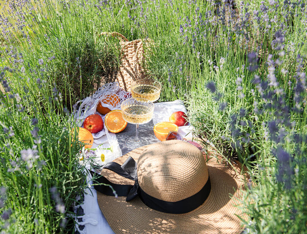 Summer picnic on a lavender field with champagne glasses and fruits - Photo, image