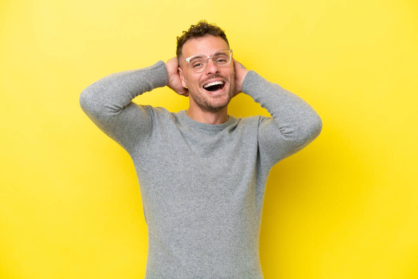 Νεαρός καυκάσιος όμορφος άντρας απομονωμένος στο κίτρινο φόντο γελώντας - Φωτογραφία, εικόνα