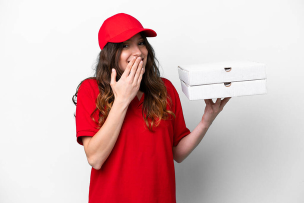 dostawca pizzy kobieta z munduru pracy podnoszenia pudełka pizzy izolowane na białym tle szczęśliwy i uśmiechnięty pokrycie usta z ręki - Zdjęcie, obraz