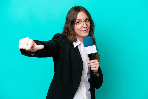 Mladý televizní moderátorka žena izolované na modrém pozadí dává palce nahoru gesto - Fotografie, Obrázek