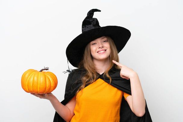 Jovem mulher bonita traje como bruxa segurando uma abóbora isolada no fundo branco dando um gesto polegar para cima - Foto, Imagem
