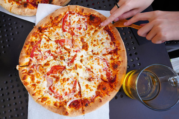 Pizza tradycyjne i autentyczne włoskie pizzy pieczone. Pizza z serem mozzarella, sosem pomidorowym, oliwą z oliwek i liśćmi bazylii. Podawana pizza na stole ze składnikami. - Zdjęcie, obraz