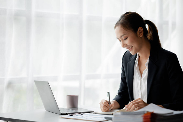 A businesswoman is checking company financial documents and using a tablet to talk to the chief financial officer through a messaging program. Concept of company financial management. - Photo, image