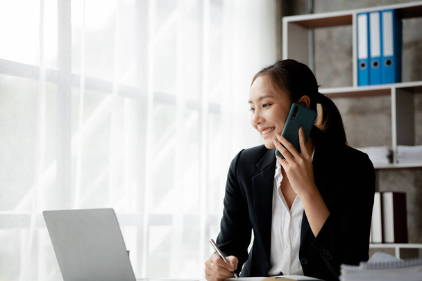 Beautiful Asian woman executives, business executives, marketing executives are talking on the phone with customers to contact the company for marketing. Marketing management concept. - Valokuva, kuva