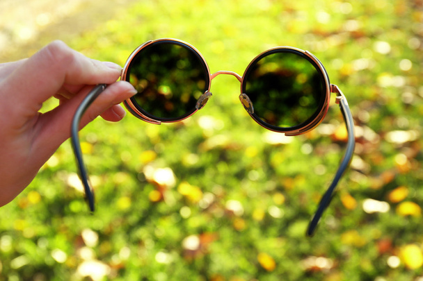 Glasses in hand on green grass background - Zdjęcie, obraz