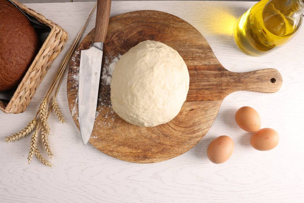 Fresh dough sprinkled with flour and other ingredients on white wooden table, flat lay - Foto, Imagen