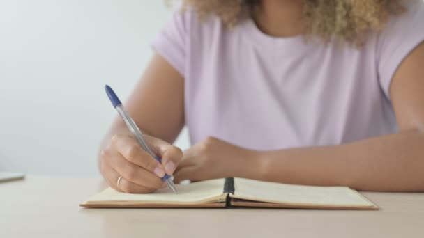 close-up van Afro-Amerikaanse vrouw schrijven op notebook - Video