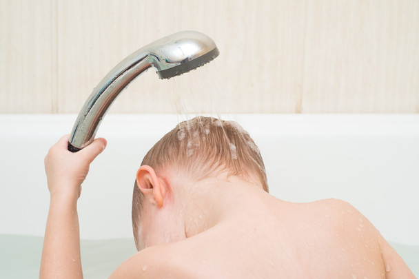 leuke 4-jarige jongen baadt in een douche - Foto, afbeelding