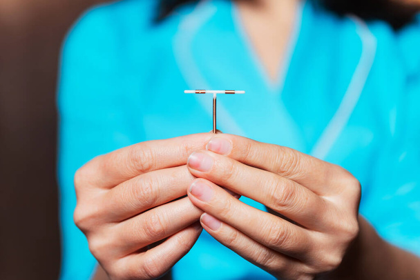 kobieca spirala antykoncepcyjna w rękach pielęgniarki. urządzenie zakazujące narodzin dziecka w rękach kobiety. wyrobu medycznego, który zapobiega zapłodnieniu jaja. antykoncepcja dla dziewcząt - Zdjęcie, obraz