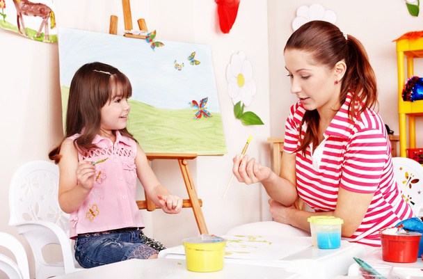 Child with teacher draw paints in play room. - Photo, Image