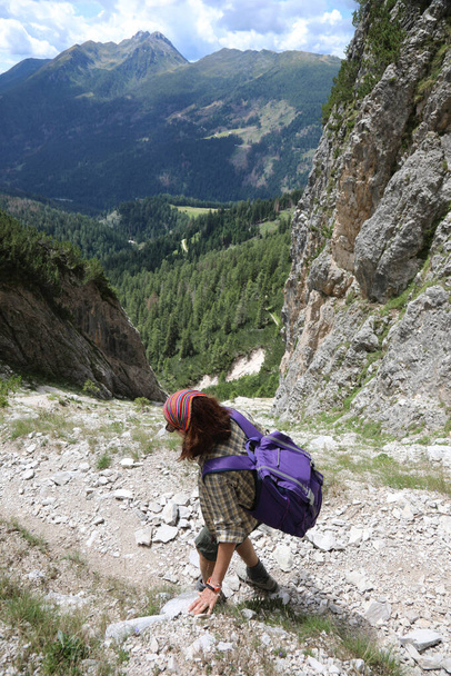 jonge vrouw met rugzak wandelingen op het grindpad in de Alpen - Foto, afbeelding