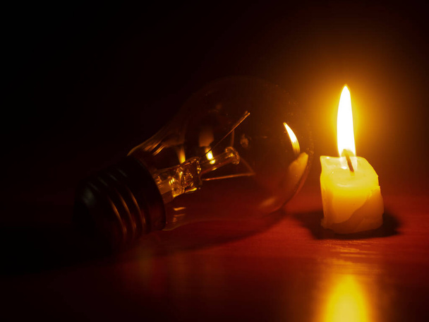Glühbirne und Kerze auf schwarzem Hintergrund - Foto, Bild