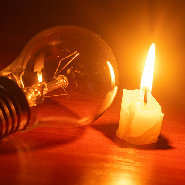 лампочка і свічка на чорному тлі
 - Фото, зображення