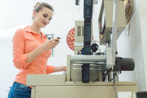 Работница проверяет текстильную этикетку только что из типографии
 - Фото, изображение