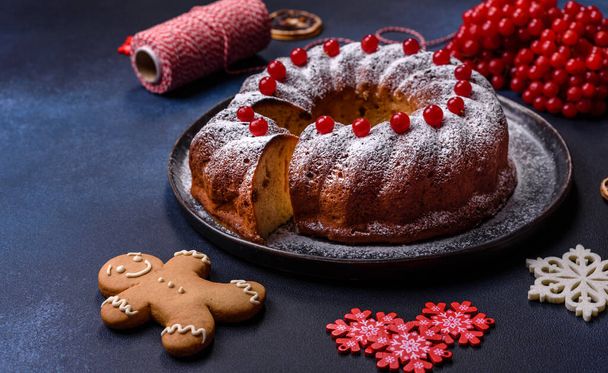 Délicieuse tarte de Noël ronde faite maison avec des baies rouges sur une assiette en céramique sur un fond de béton foncé - Photo, image