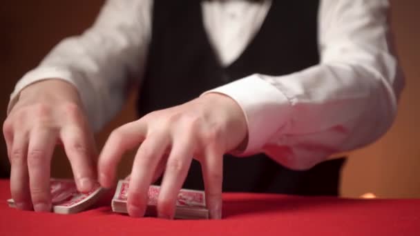 Ο ντίλερ χαρτοπαικτικών λεσχών βάζει φύλλα στο κόκκινο τραπέζι, κοντά χέρια. - Πλάνα, βίντεο