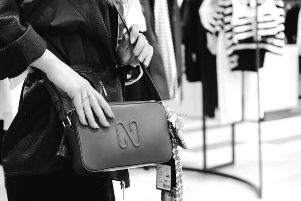 a woman wearing a bag in the store and holding the bag in her hands - Fotoğraf, Görsel