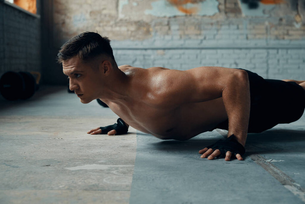 Concentrated young man doing push-up exercises in gym - Foto, Bild
