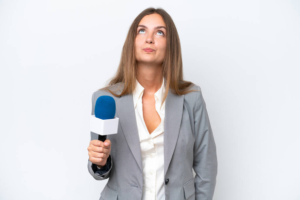 Junge TV-Moderatorin kaukasische Frau isoliert auf weißem Hintergrund und schaut auf - Foto, Bild