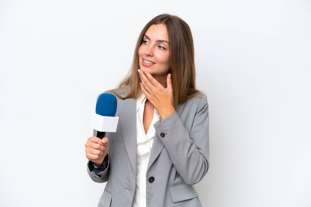 Junge TV-Moderatorin kaukasische Frau isoliert auf weißem Hintergrund sieht auf, während sie lächelt - Foto, Bild