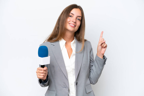 Joven presentadora de televisión mujer caucásica aislada sobre fondo blanco mostrando y levantando un dedo en señal de la mejor - Foto, Imagen