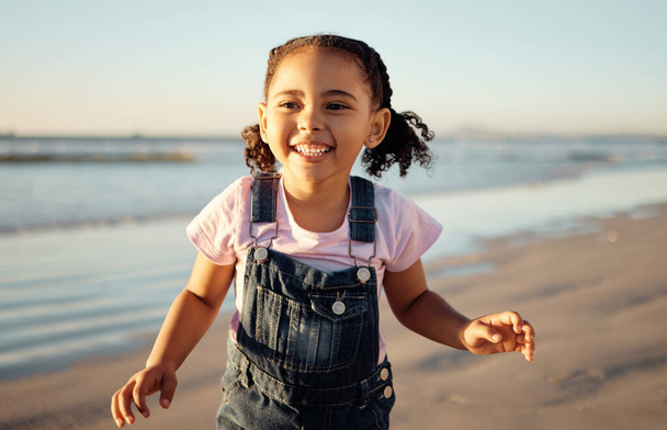 Energy, freedom and black girl running at beach, happy and excited about view of the ocean at sunset. Sea, travel and summer fun by child enjoying fresh air on a seaside getaway playing and laughing. - Фото, зображення