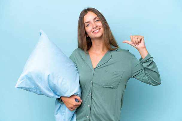 Young beautiful woman isolated on blue background in pajamas and proud of self-satisfied - Photo, Image