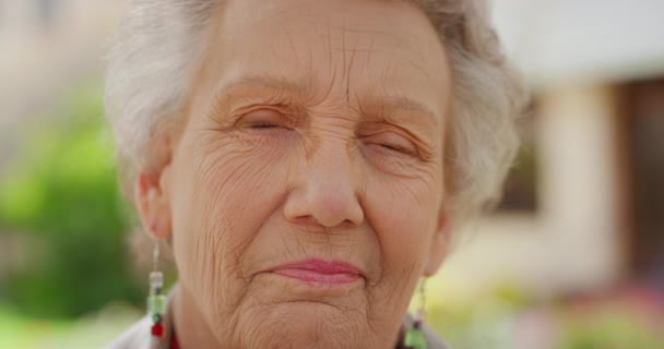 Visage, sourire et retraite avec une heureuse aînée dans le jardin de sa maison de retraite. Rides bonheur et mode de vie avec une retraitée âgée souriante et jouissant de temps libre. - Séquence, vidéo