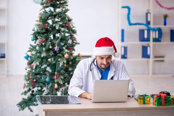 Joven médico masculino celebrando la Navidad en la clínica - Foto, Imagen