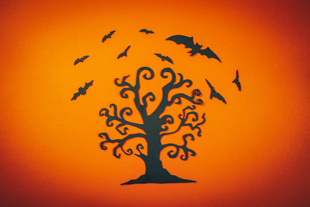Halloween albero intagliato nero con pipistrelli volanti sullo sfondo arancione.. - Foto, immagini