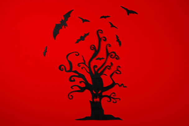 Halloween albero intagliato nero con pipistrelli volanti sullo sfondo rosso.. - Foto, immagini